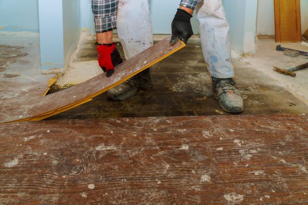 Manual worker disassembling old laminated parquet floor
