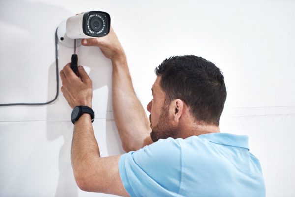Shot of a mature man installing a security camera on a building.